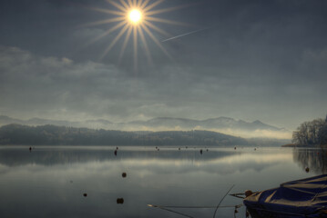 Sonnenaufgang im Winter an einem Bergsee mit Nebel und Alpenpanorama