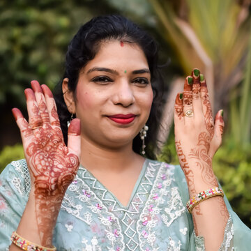 Beautiful woman dressed up as Indian tradition with henna mehndi design on her both hands to celebrate big festival of Karwa Chauth, Karwa Chauth celebrations by Indian woman for her husband
