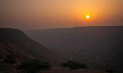 Obraz premium African valley sunset landscape with trees, hazy sky, ideal for travel projects
