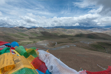 Colorful prayer flags flutter above serpentine road across Pang La Pass (5,200m) which is the last pass before reaching Mount Everest Base Camp, between Shigatse and Rongbuk, Tibet, China