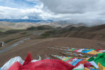 Colorful prayer flags flutter above serpentine road across Pang La Pass (5,200m) which is the last pass before reaching Mount Everest Base Camp, between Shigatse and Rongbuk, Tibet, China