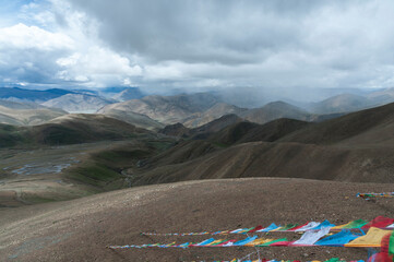 Colorful prayer flags flutter above serpentine road across Pang La Pass (5,200m) which is the last pass before reaching Mount Everest Base Camp, between Shigatse and Rongbuk, Tibet, China