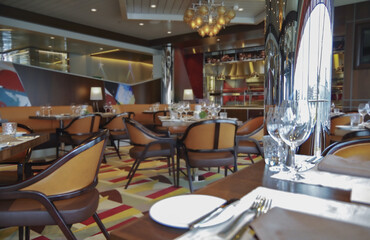 Formal and elegant Art Deco steak house speciality dining room restaurant onboard luxury cruiseship or cruise ship liner with set tables in classic interior design style and ceiling ambient lighting