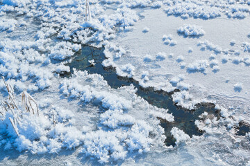Fototapeta premium Icicles and icicle crystals on frozen ice of wild stream in winter
