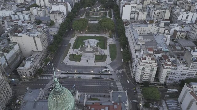Drone flies east high over National Congress, Plaza del Congreso and Plaza Mariano Moreno after sunset in Buenos Aires, Argentina