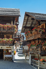 Village traditionnel valaisan de montagne avec des vieux chalets en bois et des géranium aux balcons