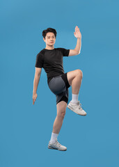 ImageFull body image of Asian guy wearing workout clothes and posing on a blue background