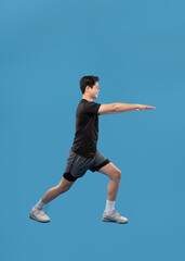 Fototapeta premium ImageFull body image of Asian guy wearing workout clothes and posing on a blue background