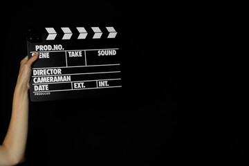 Woman with clapperboard on black background, closeup. Space for text