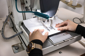 Woman working with sewing machine in professional workshop, closeup