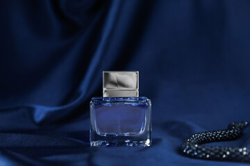 Bottle of perfume and dark blue silk fabric
