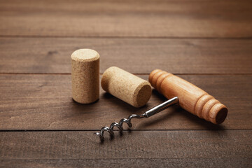 Corkscrew with handle and corks on wooden table