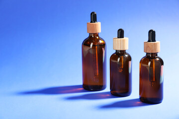 Bottles of skin care products on blue background, space for text