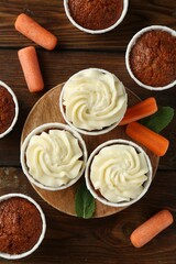 Tasty carrot muffins and fresh vegetables on wooden table, flat lay