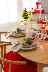 Christmas celebration. Festive table setting with dishware, glasses and decor in room