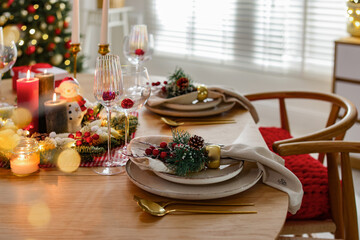 Christmas celebration. Festive table setting with dishware, glasses and decor in room