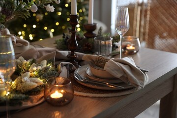 Christmas place setting with festive decor on wooden table in room