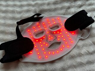 Led light therapy face mask on soft fabric, top view. Beauty treatment