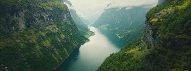 A breathtaking aerial perspective of the Norwegian fjords in Geiranger, Norway, with steep cliffs and emerald-green waters under the soft light of a summer morning