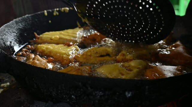 Bread pakora is being fried in hot oil. It is made by stuffing the bread with potatoes and dipping it in the batter of chickpea flour and then frying it. popular snack of India. Slow motion video. 