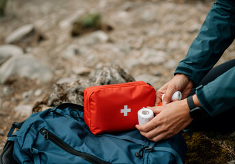 Close up of hiker taking bandages from first aid kit during hike