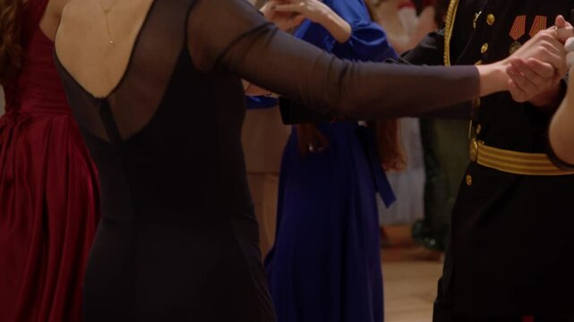 A group of reenactors dance an old dance together, creating the atmosphere of a festive reception or ball from centuries past.