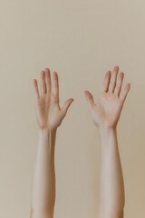 Two hands raised against a neutral background, suggesting openness or a greeting.