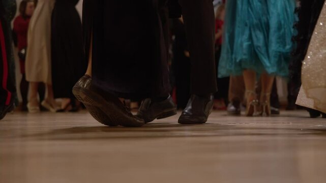 Close-up of couples' legs dancing at a waltz ball, dressed in vintage shoes and dresses.