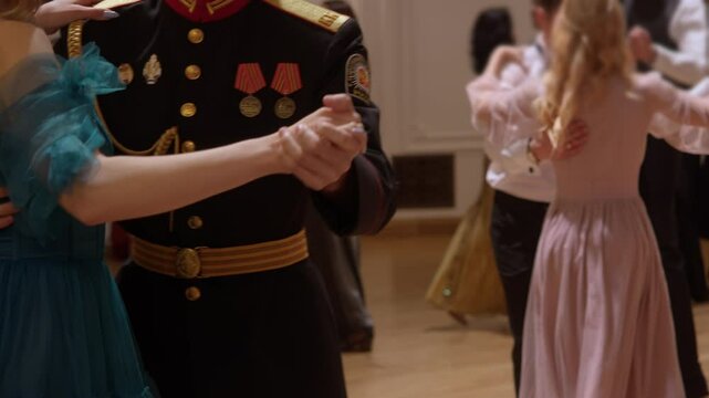 Military man is dancing pair dance with his loved one in their full dress uniform, with medals on their shoulder straps, at vintage-style ball.