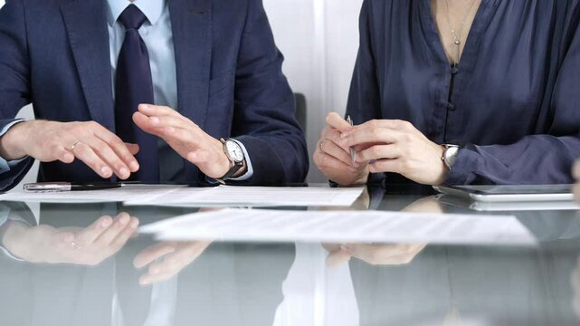 Business partners or lawyers are discussing contract papers during a meeting, negotiating and making decisions together. Business people concept, close up