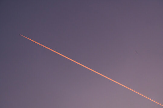 Airplane trail in a violet sky with the bright planet Venus in Geneva