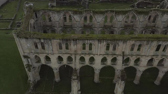 Drone shot of the historic ruins of Rievaulx Abbey with lush green surroundings in North Yorkshire, UK