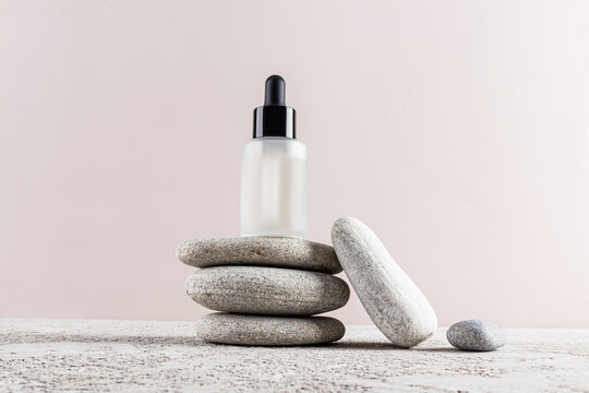 Minimalist skincare concept with serum dropper bottle on stones