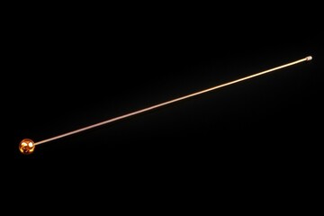 Fototapeta premium Long golden pin with a round head on a black background.