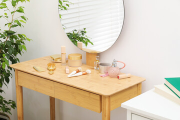 Mirror, dressing table with cosmetic products and houseplant indoors. Interior design