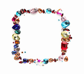 Frame of different shiny gemstones on white background, flat lay. Space for text