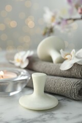 Spa stones, orchid flowers, towels and burning candle on white marble table, closeup