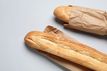 Paper bags with fresh baguettes on white background, top view