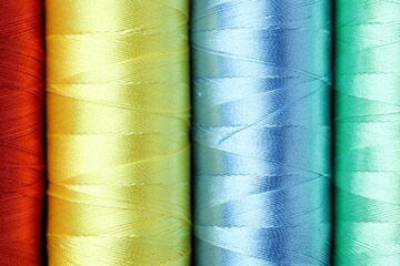 Spools of colorful sewing threads as background, top view