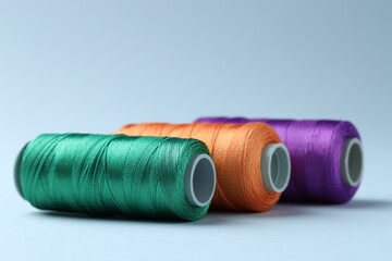 Spools of colorful sewing threads on light background, closeup