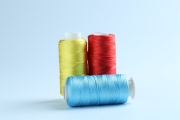 Spools of colorful sewing threads on light background