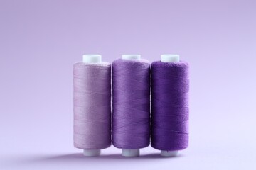 Spools of colorful sewing threads on lilac background