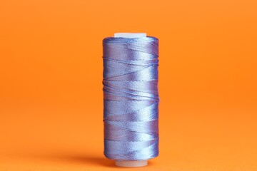 Spool of blue sewing thread on orange background