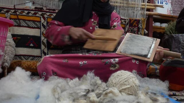 Africa , Morocco,Dades Dra Valley 01,06,2025 Tuareg Berber woman works wool by carding and creates a thread for the pruning of carpets and fabrics for artefacts, traditional Moroccan manufacturing art