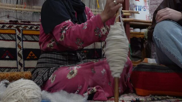 Africa , Morocco,Dades Dra Valley 01,06,2025 Tuareg Berber woman works wool by carding and creates a thread for the pruning of carpets and fabrics for artefacts, traditional Moroccan manufacturing art