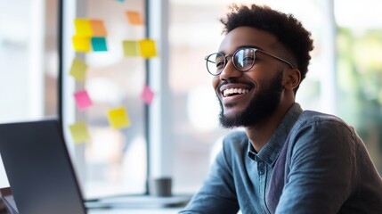 Smiling person brainstorming in a modern coworking space, with sticky notes, laptops