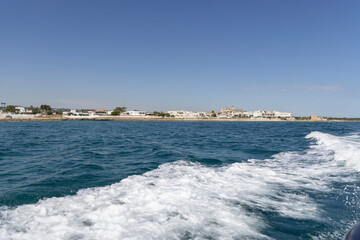 Picturesque view from the boat of the Adriatic Sea with a wake and the coast, Polignano a Mare, Italy, Apulia