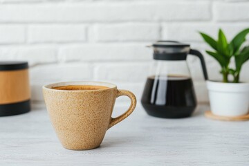 Obraz premium Cup of freshly brewed coffee sitting on white table with bistro backdrop