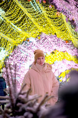 Young smiling happy girl in Christmas decorated with holiday lights. New Year's Eve, festive atmosphere