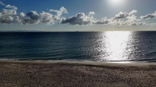 Ein Strand in Tarifa, Valdevaqueros, mit Blick auf Afrika. Die untergehende Sonne wirft goldene Farben &uuml;ber den Ozean. Der Strand ist von sanften Wellen und einer ruhigen Atmosph&auml;re gepr&auml;gt.